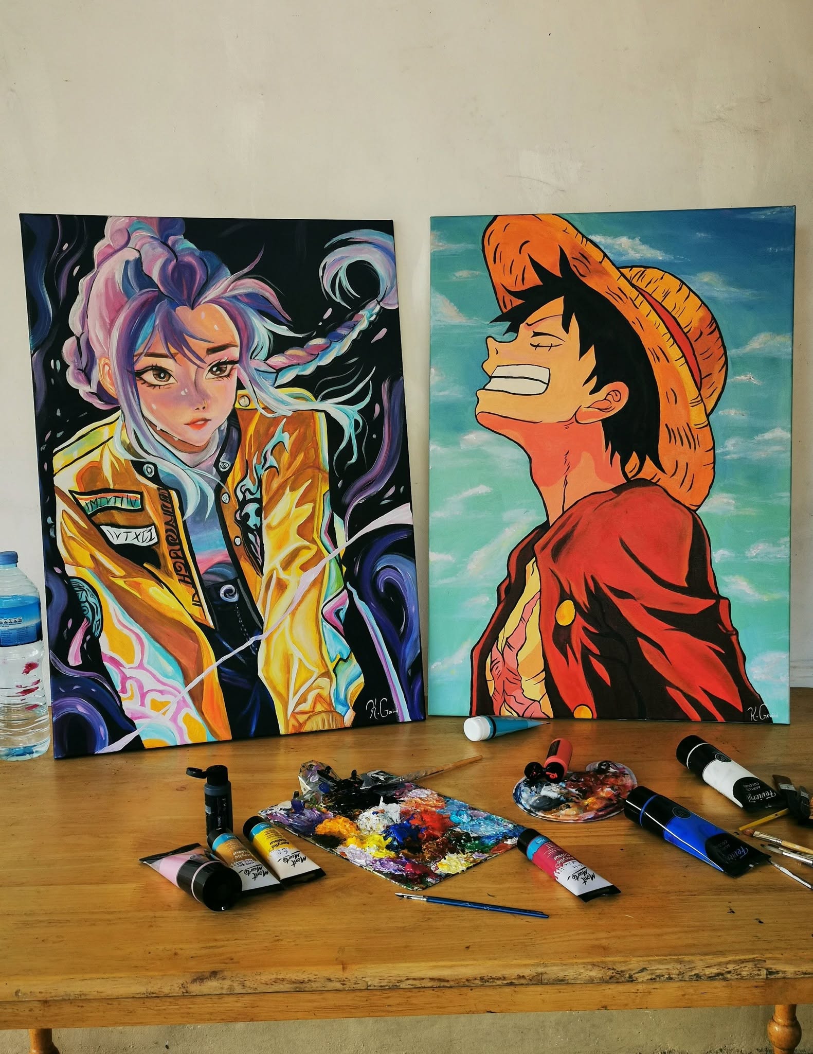 Two hand-painted anime-inspired character portraits on canvases, displayed with painting supplies